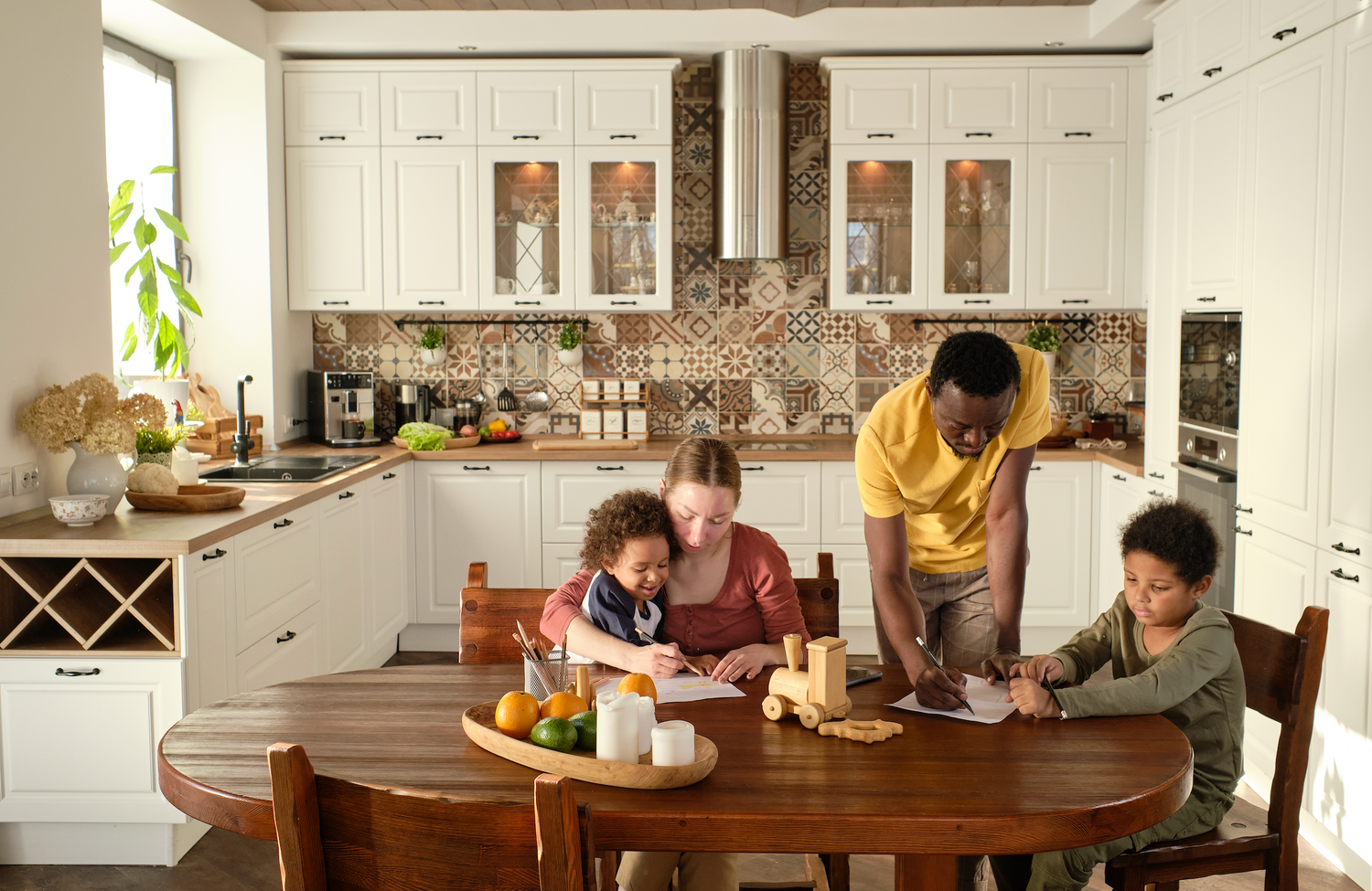 Family of four in a modern kitchen with children at a table.